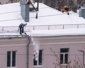 Team,Of,Male,Workers,Clean,Roof,Of,Building,From,Snow